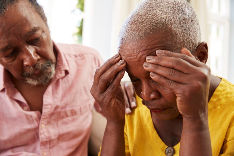 Woman with face in hands stressed out and upset being comforted by senior man